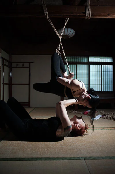 Isabelle Hanikamu is lying on the tatamis mats under Iroha who is suspended in the old house of Roppongi. They look each others in the eyes.