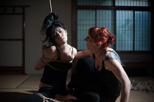 Isabelle Hanikamu 井佐鐘 is sitting beside Iroha on the tatamis mats during a. shibari practice in the old house of Roppongi.